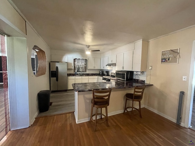 78 Duncan St, Fort Valley, GA 31030 - kitchen featuring stainless steel appliances, a peninsula, dark wood-style flooring, crown molding, and white cabinets