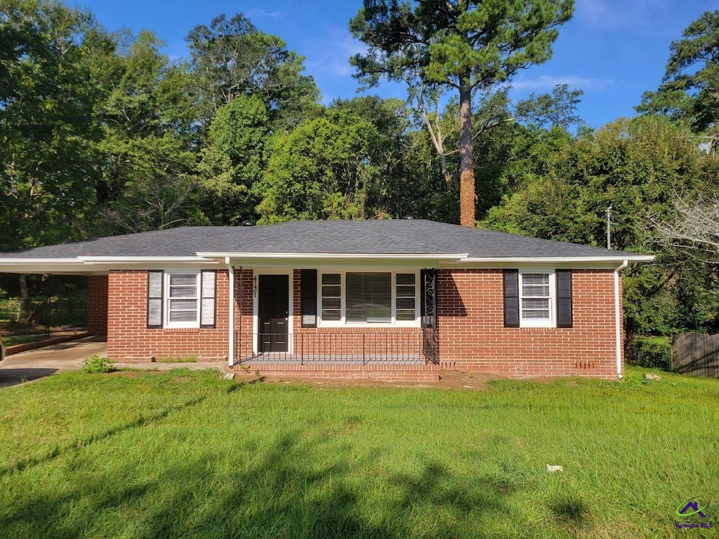 single story home with an attached carport, covered porch, brick siding, and a front yard