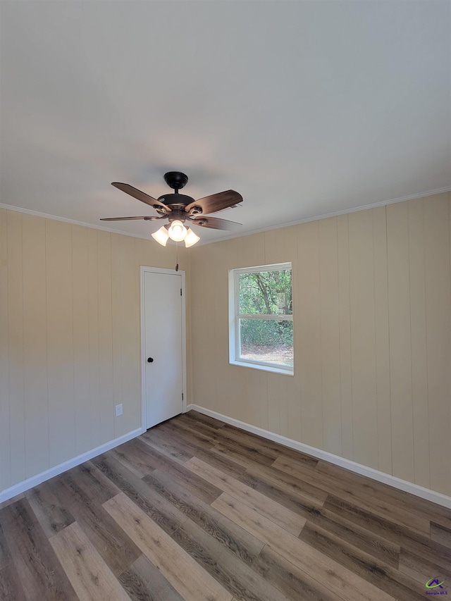 empty room featuring baseboards, ornamental molding, wood finished floors, and a ceiling fan