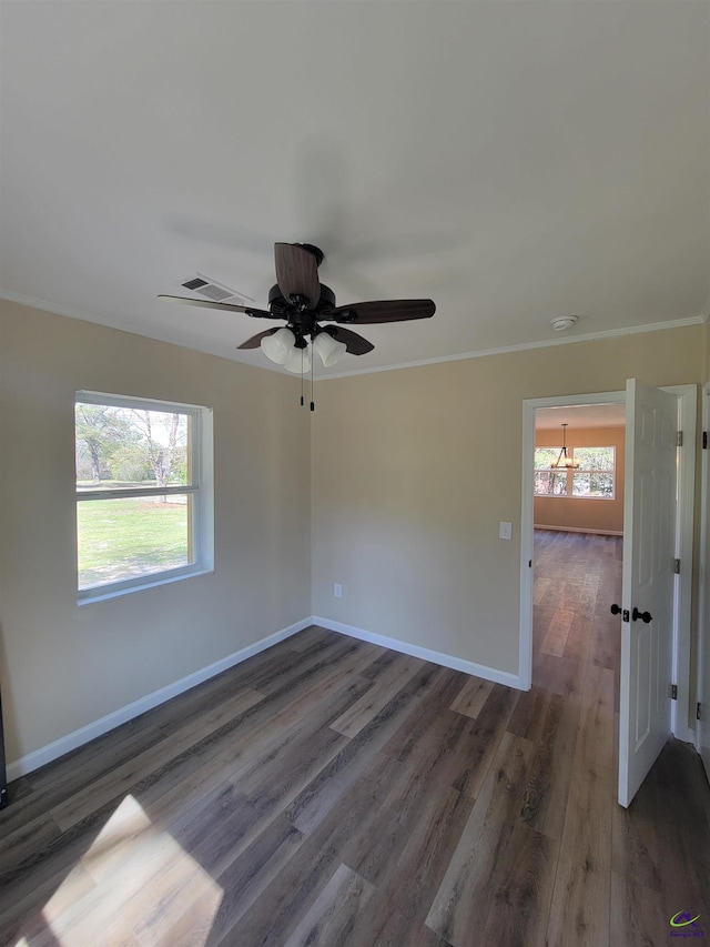unfurnished room featuring a ceiling fan, wood finished floors, baseboards, visible vents, and ornamental molding