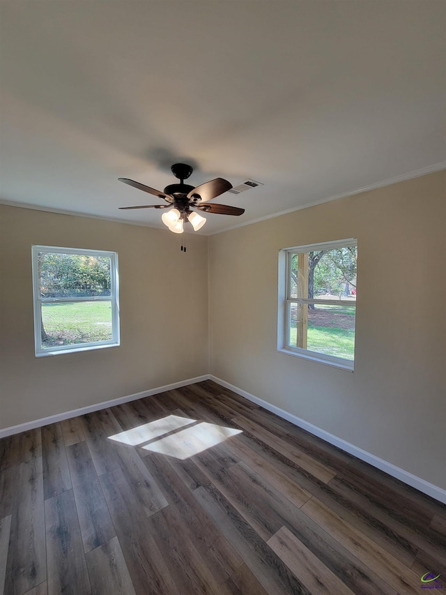 spare room with crown molding, baseboards, dark wood finished floors, visible vents, and a ceiling fan