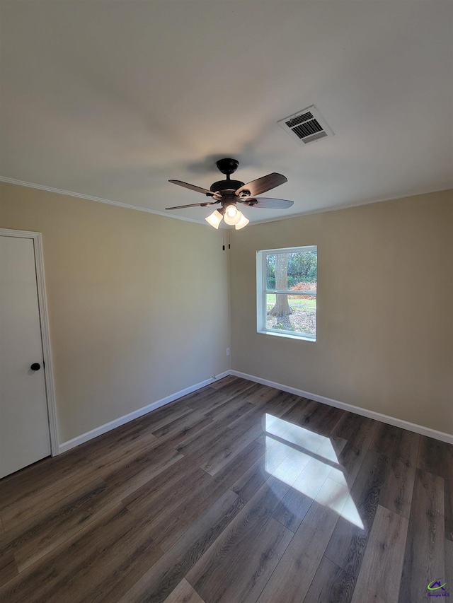 unfurnished room with crown molding, dark wood finished floors, baseboards, visible vents, and ceiling fan