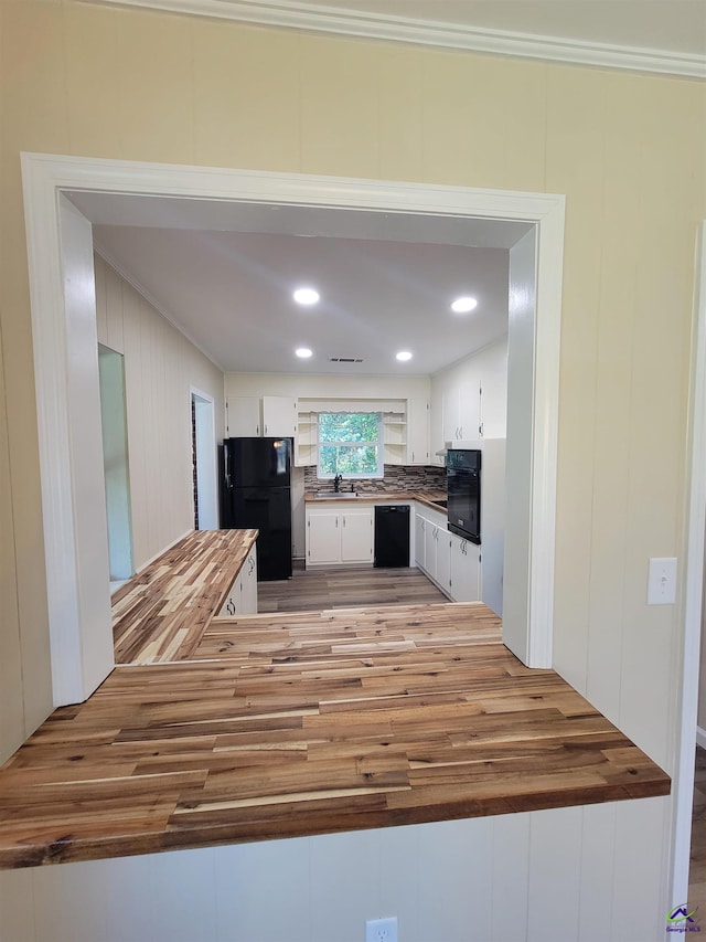 kitchen with a sink, white cabinetry, black appliances, and light wood-type flooring