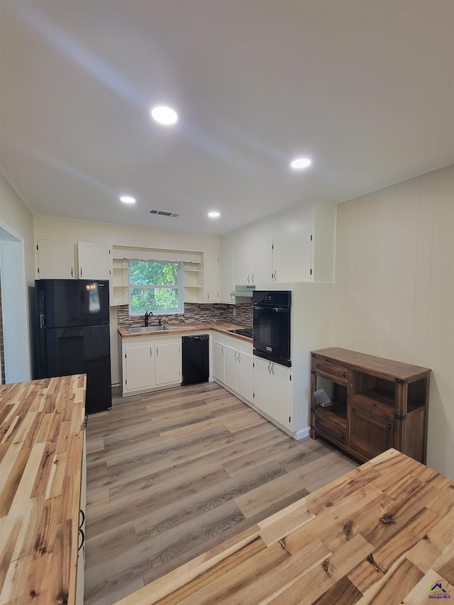 kitchen with white cabinets, visible vents, light wood finished floors, a sink, and black appliances
