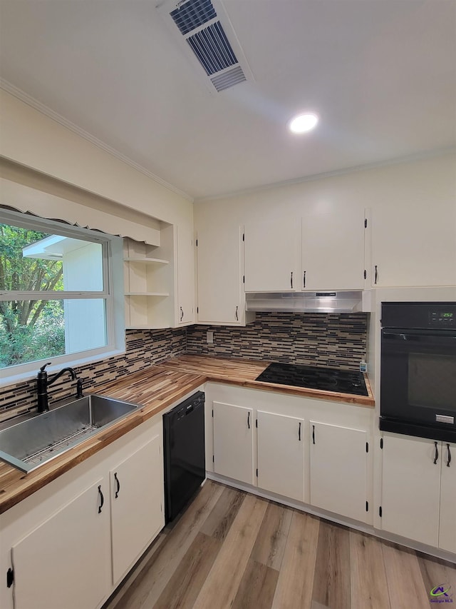 kitchen featuring under cabinet range hood, a sink, wood counters, visible vents, and black appliances
