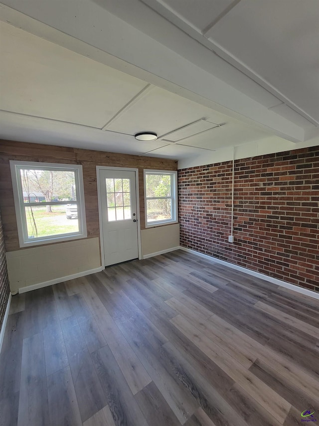 interior space featuring baseboards, wood finished floors, and brick wall