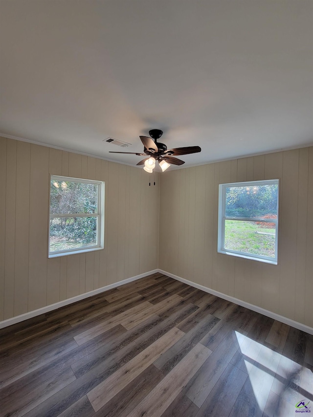 empty room with baseboards, visible vents, ceiling fan, and wood finished floors