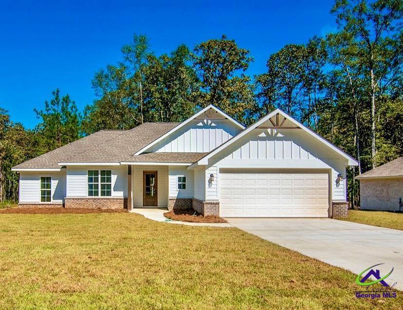 view of front of home with brick siding, board and batten siding, concrete driveway, and a front yard