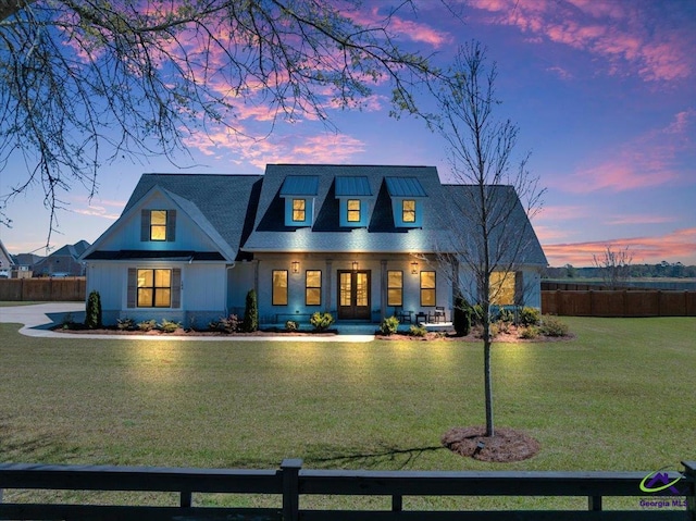 view of front of house with french doors, covered porch, fence, and a lawn
