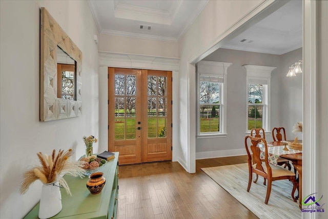 entryway with baseboards, visible vents, crown molding, and wood finished floors