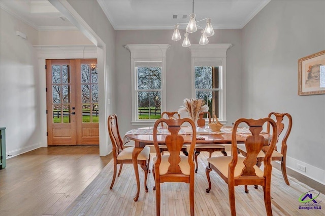 dining room with light wood finished floors, baseboards, crown molding, and french doors