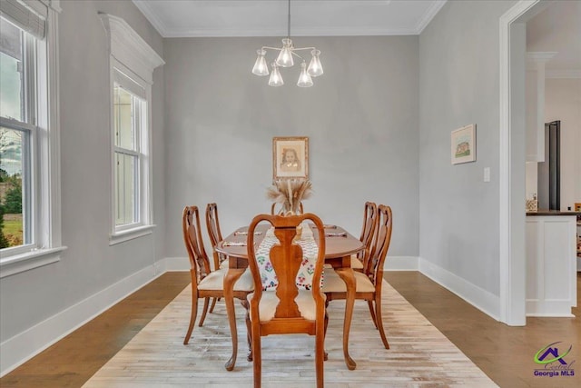 dining space with baseboards, ornamental molding, wood finished floors, and an inviting chandelier