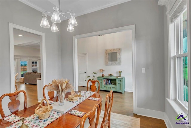 dining room featuring crown molding, baseboards, a chandelier, and wood finished floors