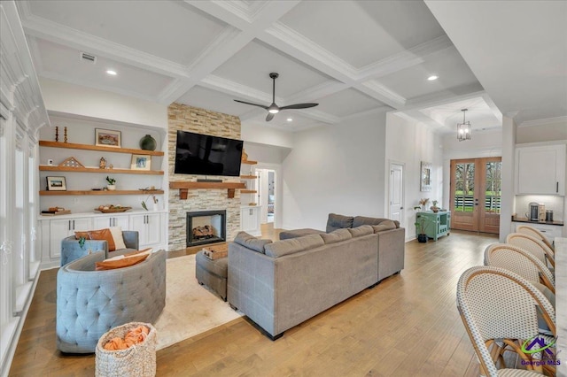 living room with coffered ceiling, light wood-type flooring, beamed ceiling, ceiling fan, and a fireplace