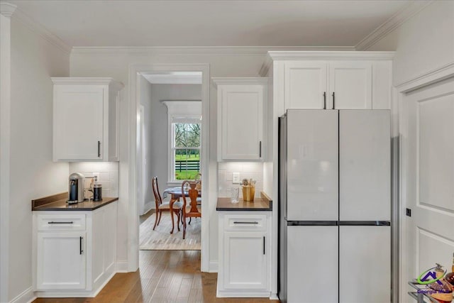kitchen with dark countertops, decorative backsplash, white cabinetry, and freestanding refrigerator