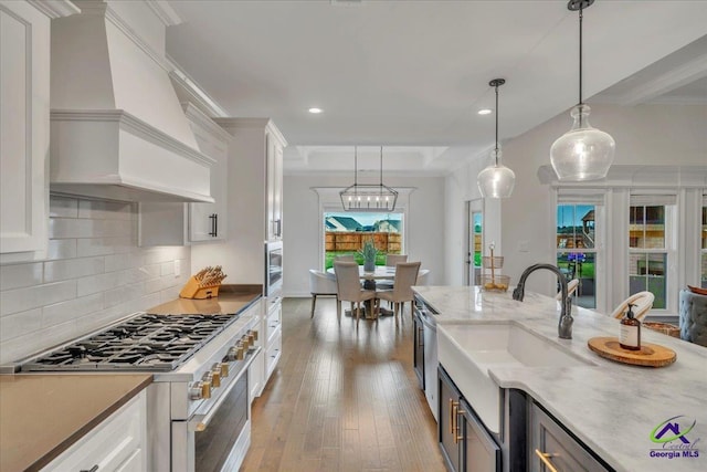 kitchen featuring a sink, appliances with stainless steel finishes, light wood-style flooring, custom range hood, and white cabinets