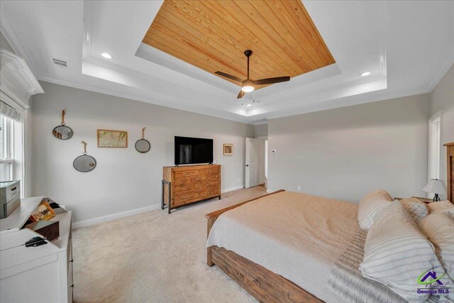 bedroom with a raised ceiling, baseboards, and light colored carpet