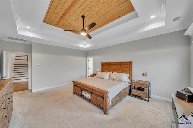 bedroom with a tray ceiling, visible vents, and light colored carpet