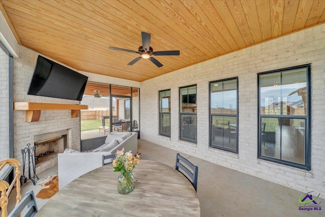 view of patio with an outdoor brick fireplace, outdoor dining area, fence, and ceiling fan