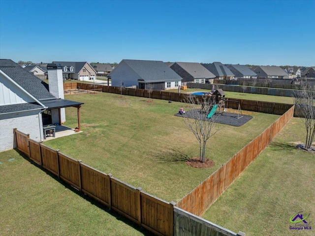 view of yard with a fenced backyard, a playground, and a residential view