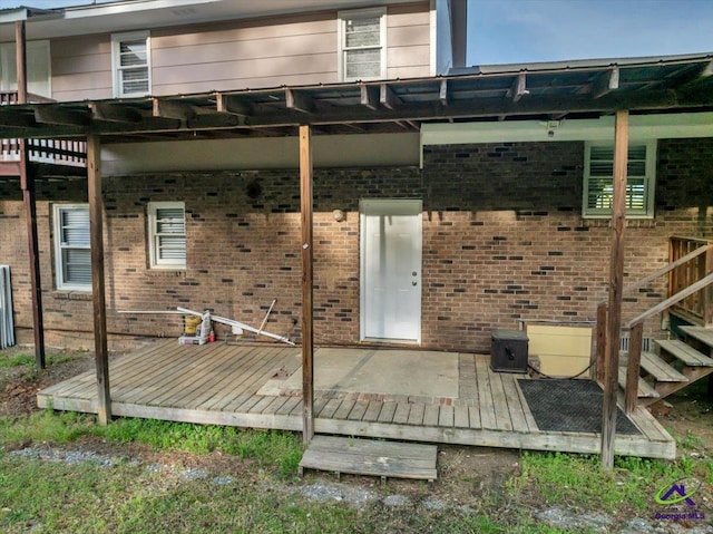 rear view of property featuring a wooden deck and brick siding
