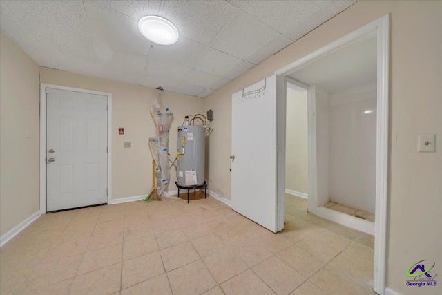 interior space with water heater, baseboards, a paneled ceiling, and light tile patterned flooring