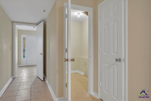 corridor featuring baseboards and light tile patterned floors