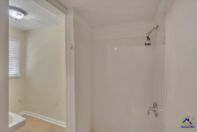 full bath with baseboards and tiled shower