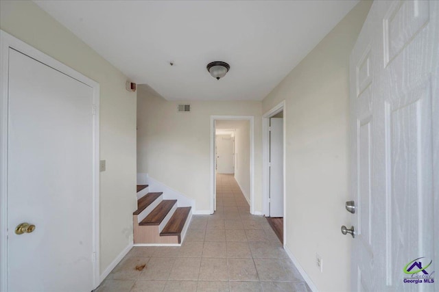 hall with light tile patterned flooring, visible vents, and baseboards
