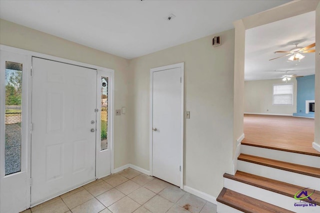 foyer with baseboards, stairway, light tile patterned floors, and a ceiling fan