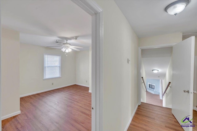 hallway with baseboards, an upstairs landing, and wood finished floors