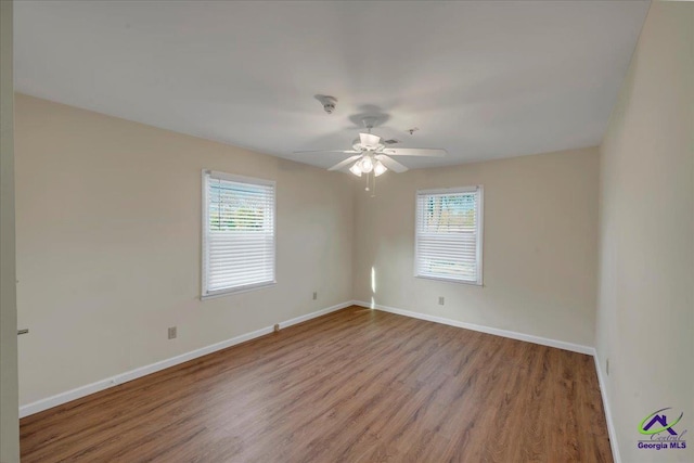 spare room with a wealth of natural light, wood finished floors, and baseboards
