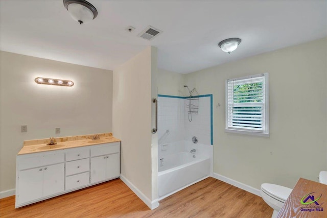 bathroom with shower / bath combination, toilet, a sink, visible vents, and wood finished floors