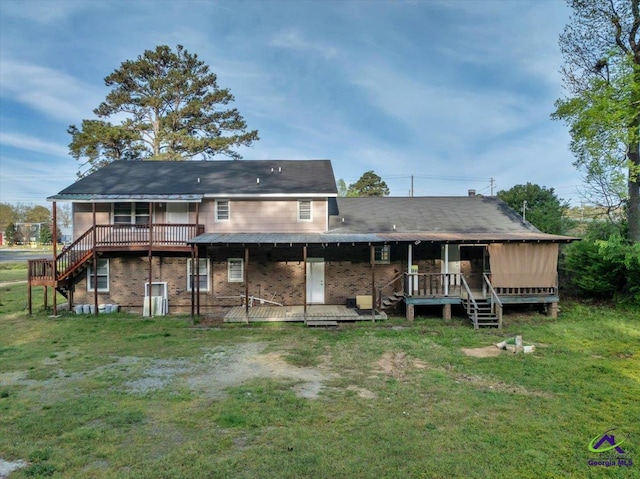 rear view of house featuring a deck, brick siding, and a yard