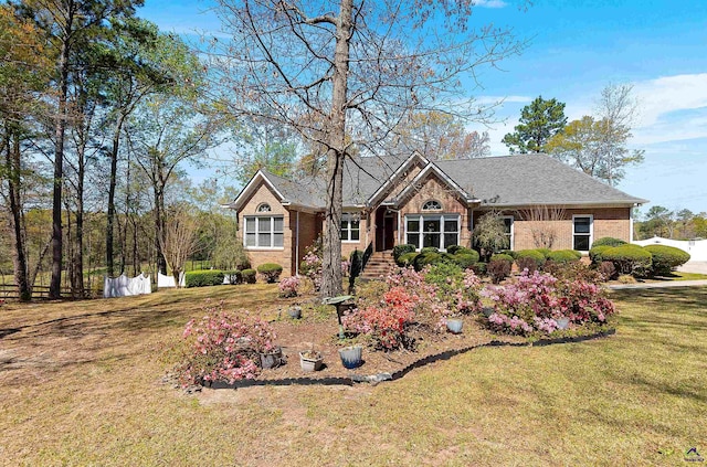 single story home featuring a front yard, fence, and brick siding