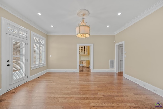 unfurnished dining area featuring light wood finished floors, baseboards, visible vents, and crown molding