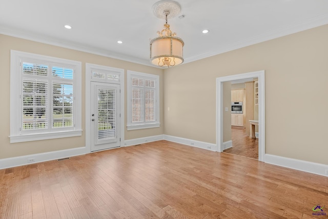 spare room with visible vents, ornamental molding, baseboards, and wood finished floors
