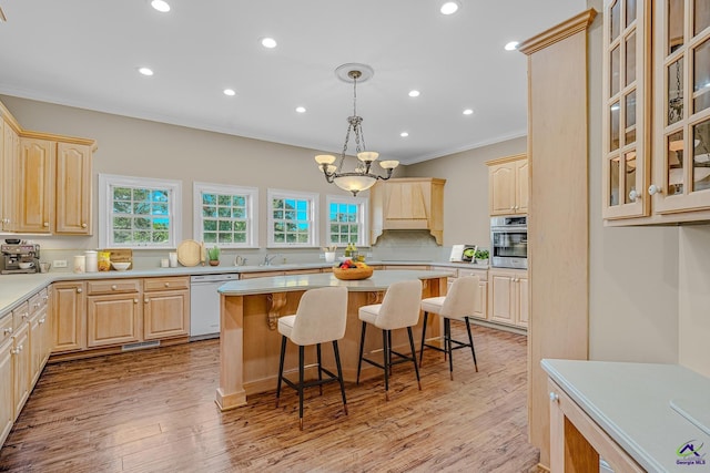 kitchen with light brown cabinets, white dishwasher, a breakfast bar, and oven
