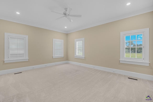 carpeted empty room with baseboards, visible vents, ceiling fan, and ornamental molding