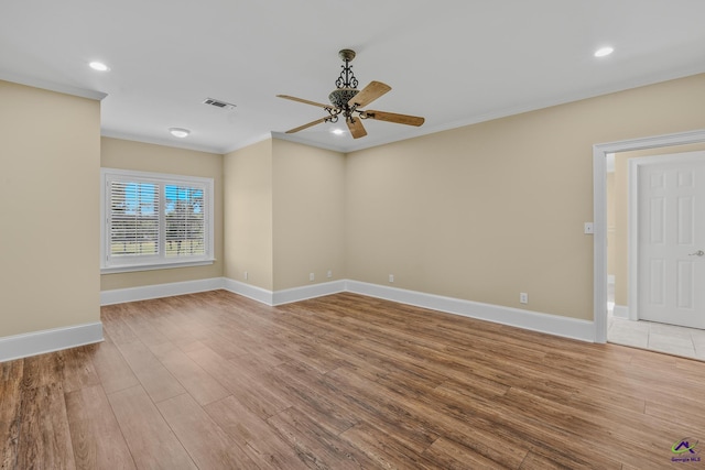 spare room with crown molding, wood finished floors, baseboards, visible vents, and ceiling fan