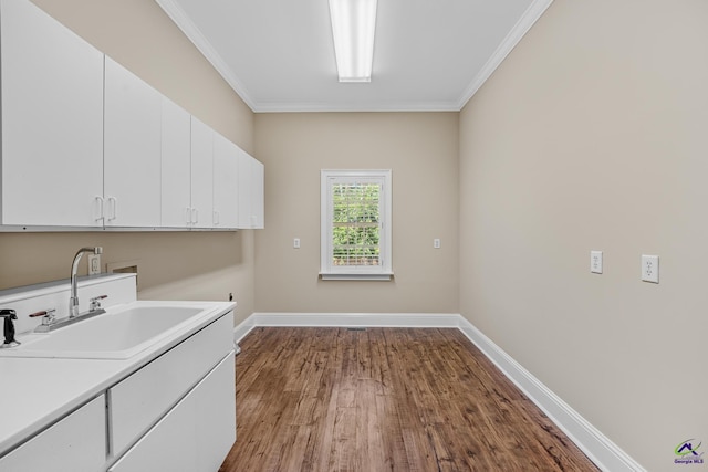 laundry room with washer hookup, baseboards, ornamental molding, a sink, and cabinet space