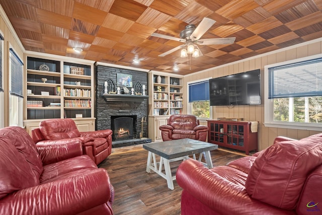 living room featuring wood walls, built in shelves, wood finished floors, a stone fireplace, and wooden ceiling