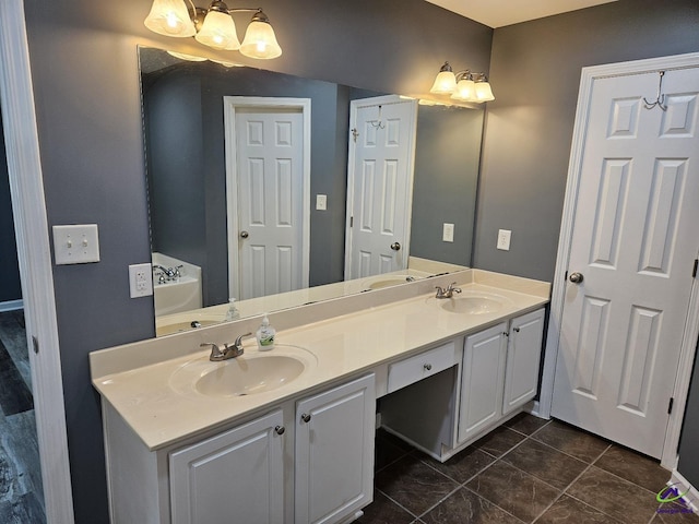 bathroom featuring a bath, double vanity, a notable chandelier, and a sink