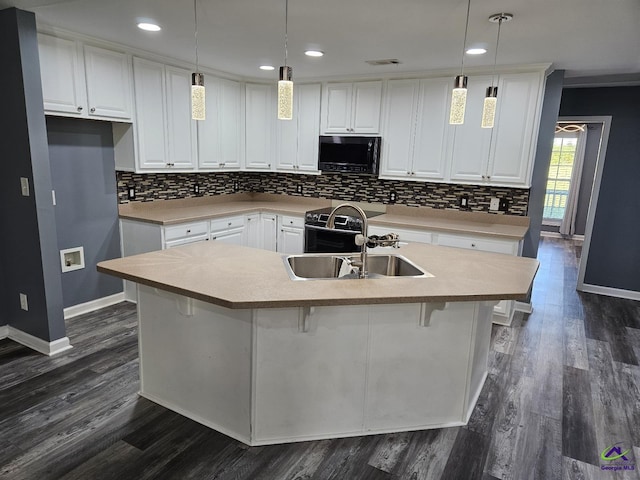 kitchen featuring tasteful backsplash, baseboards, a sink, dark wood finished floors, and black microwave