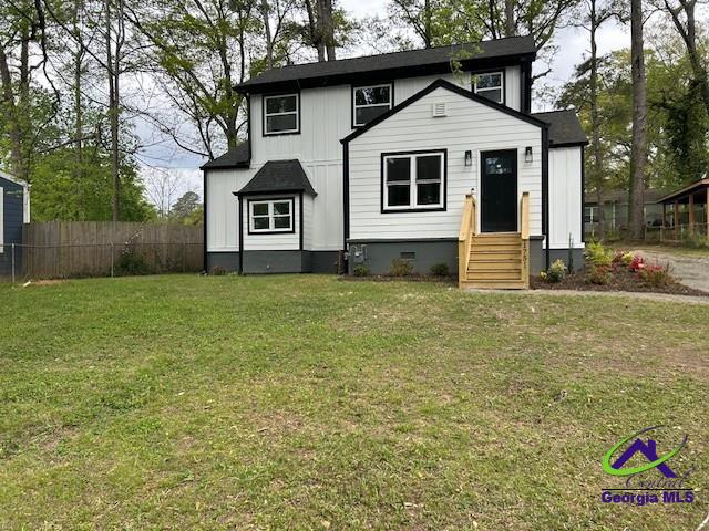 view of front of property with a front yard, fence, and entry steps