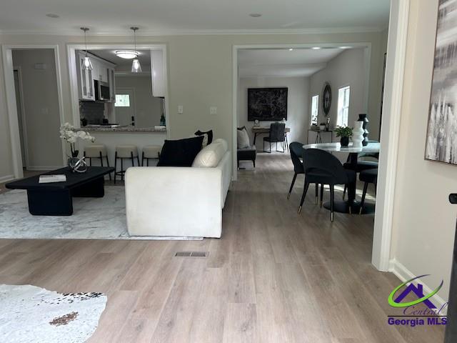 living room with ornamental molding and wood finished floors
