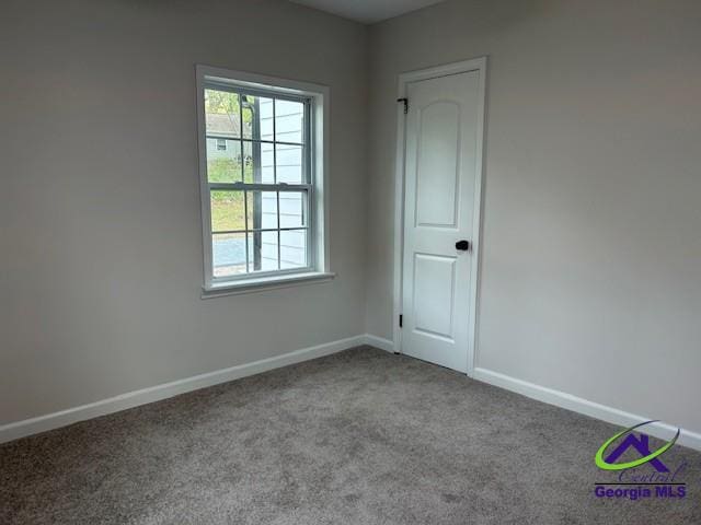 empty room featuring carpet floors, baseboards, and a wealth of natural light