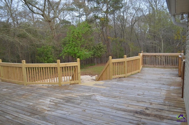 wooden terrace featuring a wooded view and fence
