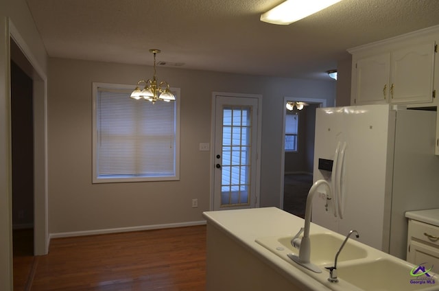 kitchen featuring visible vents, white fridge with ice dispenser, white cabinets, and a notable chandelier