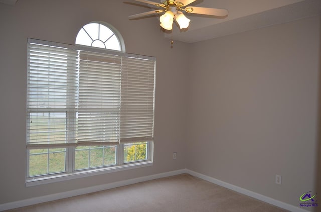 spare room with baseboards, a ceiling fan, plenty of natural light, and light colored carpet